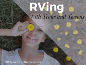 A smiling teen sitting by an RV campfire holding a marshmallow stick or hot cocoa.