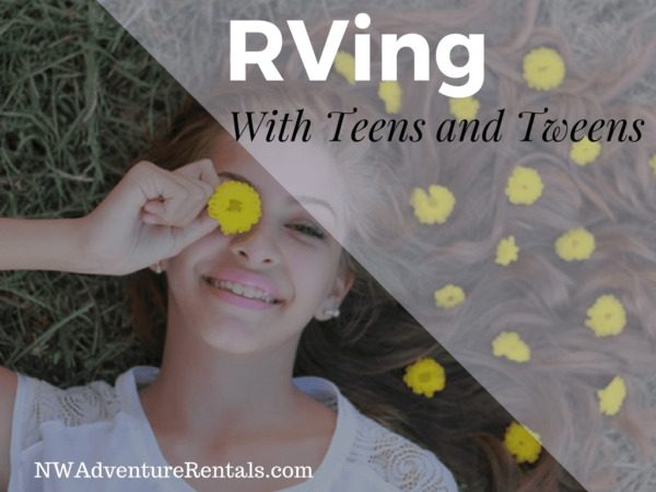 A smiling teen sitting by an RV campfire holding a marshmallow stick or hot cocoa.
