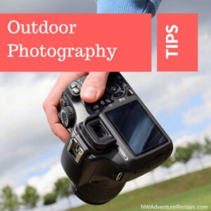 Person holding a DSLR camera outdoors, preparing to take landscape photos.